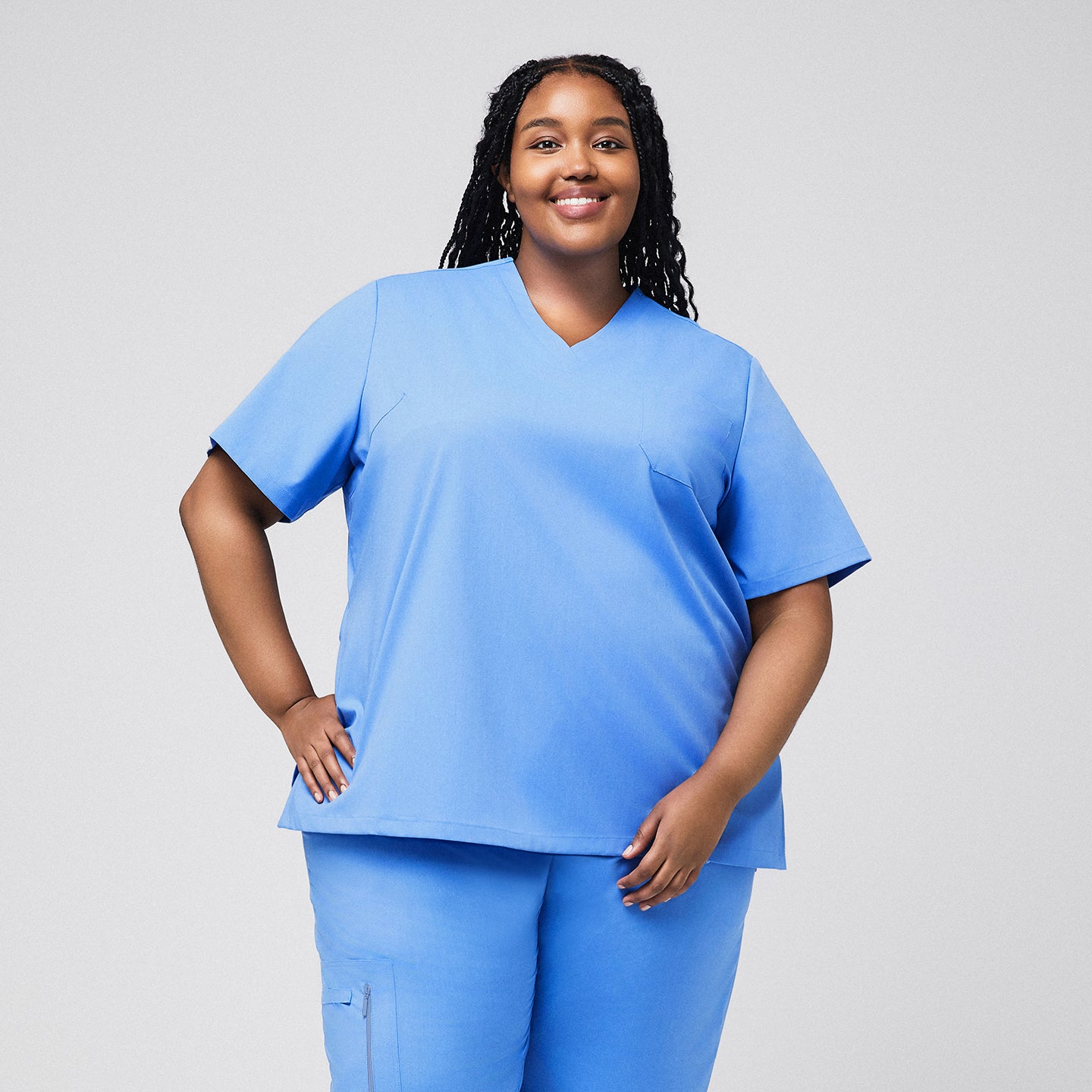 Image of Plus-size model wearing a light blue 3-pocket scrub top and matching pants, offering a comfortable and practical outfit for healthcare professionals,Ceil Blue